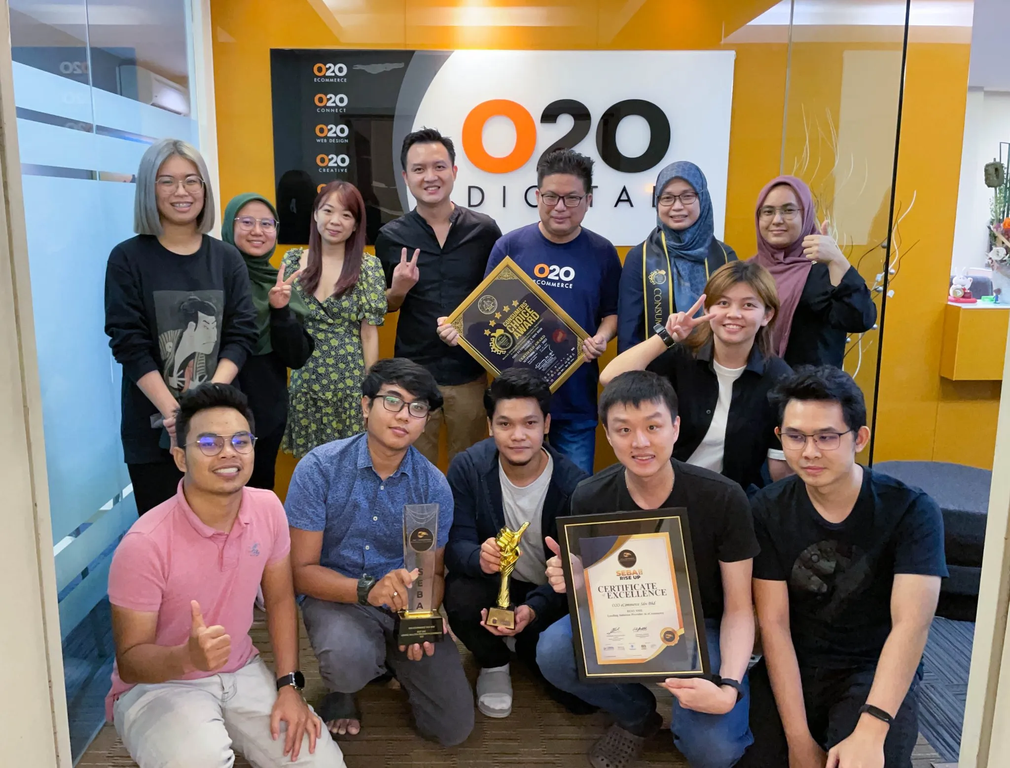 O2O Digital team holding award trophies and certificates in the office