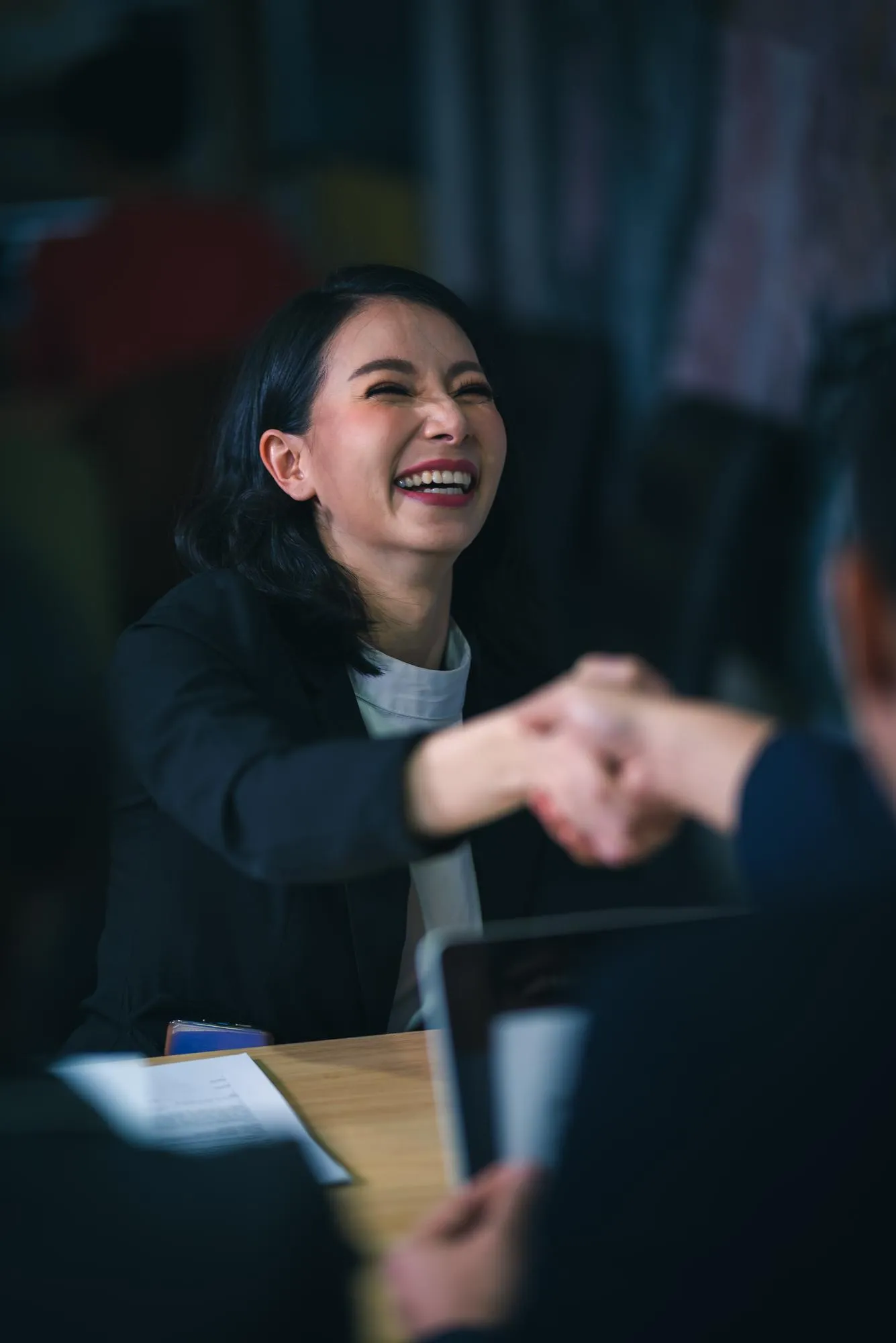 Smiling businesswoman shaking hands across a desk