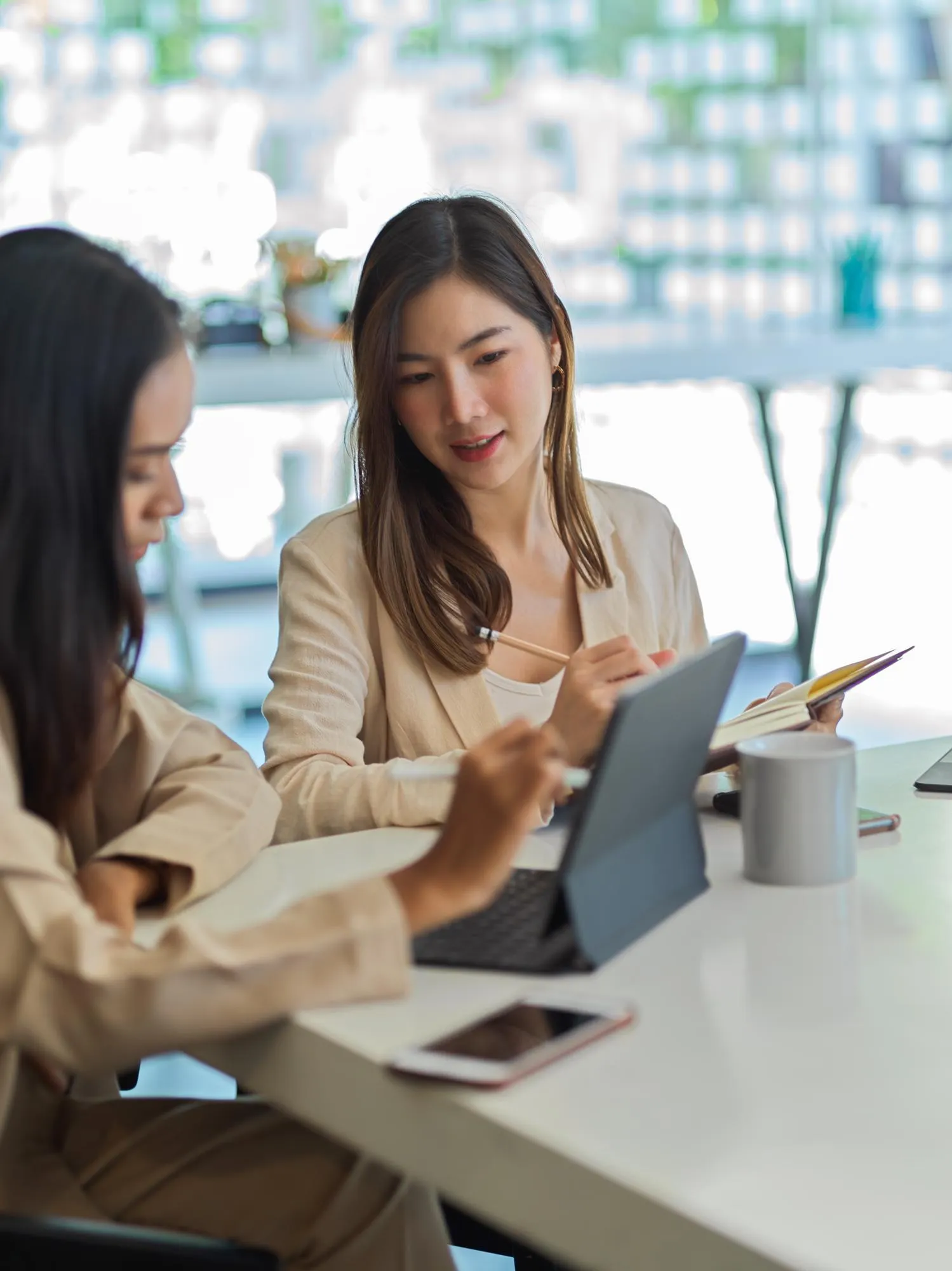 Two colleagues discussing ideas over a tablet at a café table