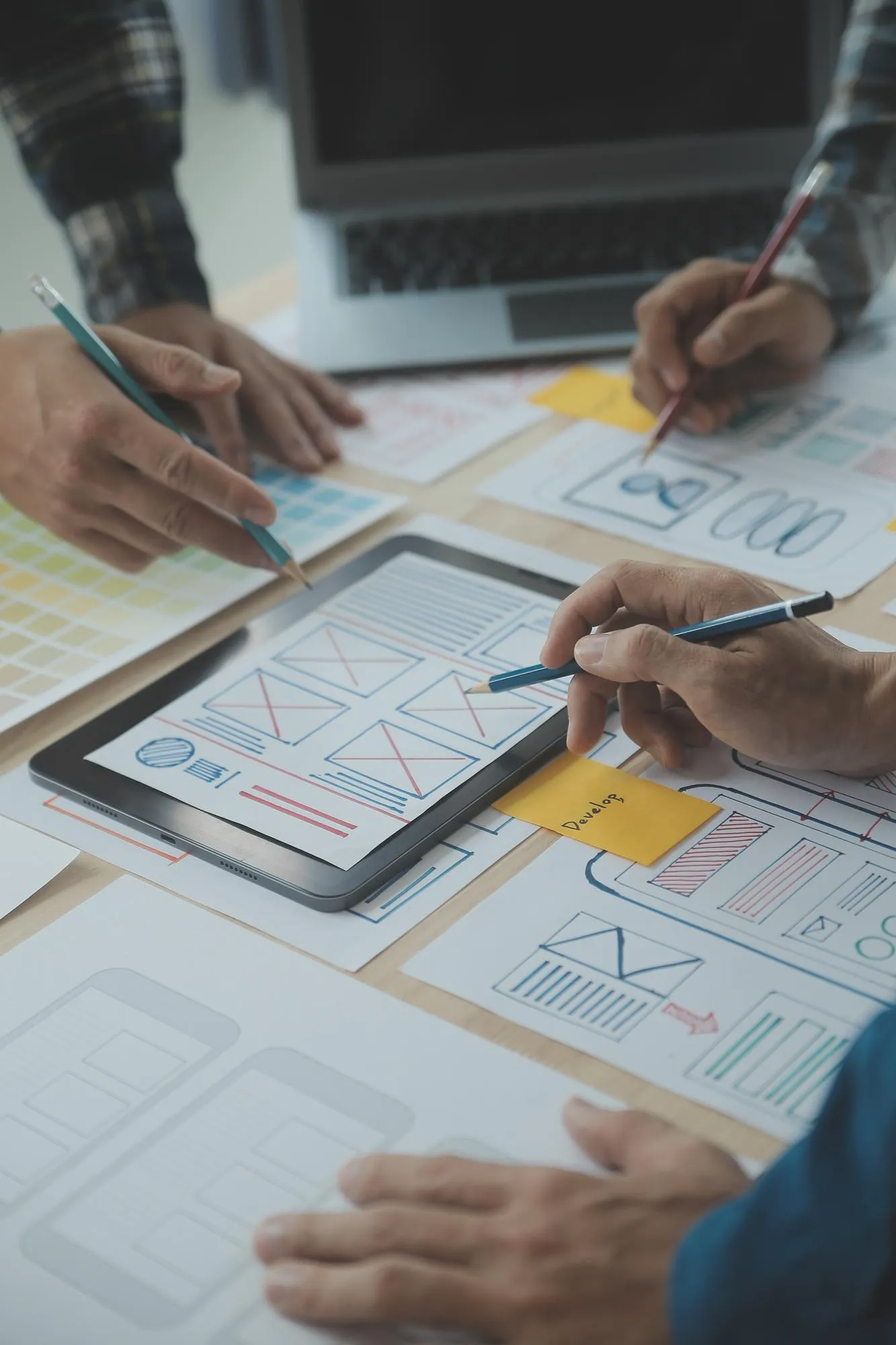 Designers sketching website wireframes on paper and a tablet